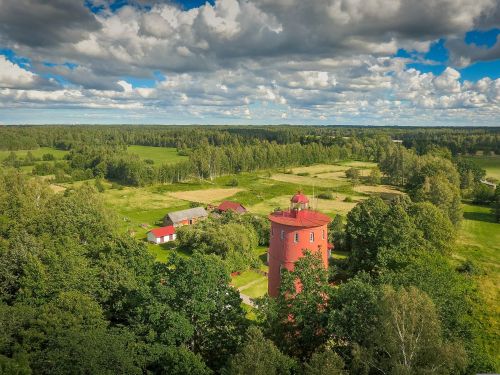 An aerial photo of Slītere lighthouse, surrounding farmland and vegetation.