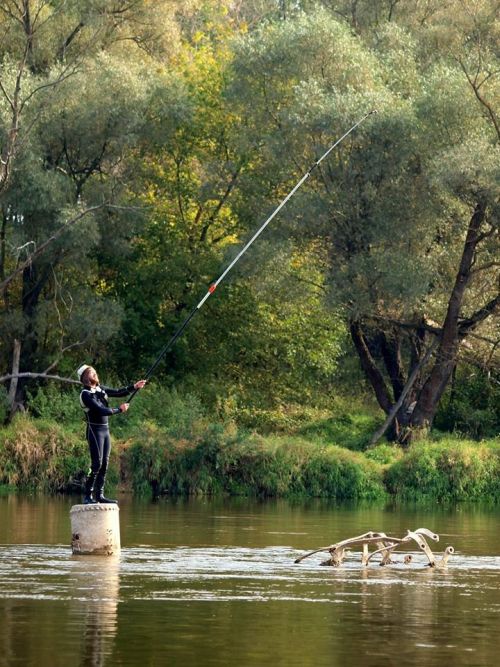 man standing on shipwreck with sensor attached to long pole